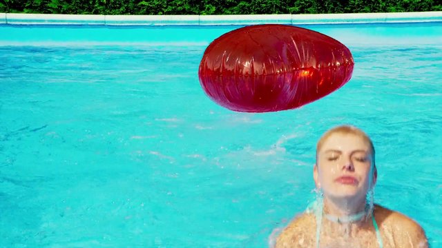 Video Reference: swimming pool, water, inflatable ball, red ball, person, outdoor, summer, recreation, floating, blue water, close-up, leisure
