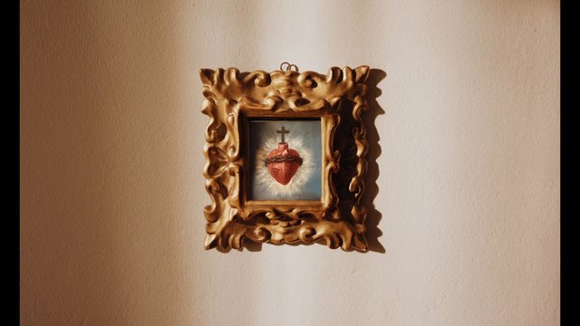 Video Reference: ornate frame, wall art, religious icon, sacred heart, cross, interior decor, gold frame, beige wall, portrait orientation, vintage style, home decoration