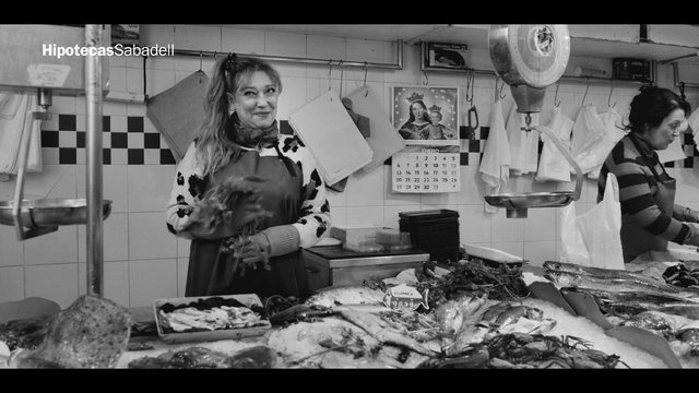 Video Reference: fish market, seafood, vendor, women, indoor market, black and white, fresh fish, counter, market stall, working, apron, watermark, commercial kitchen, food display, retail