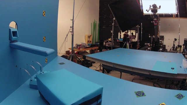 Video Reference: film set, studio, production, lighting rig, camera equipment, blue set, backstage, crew, soundstage, props, green screen, studio lighting, cinematography, set design