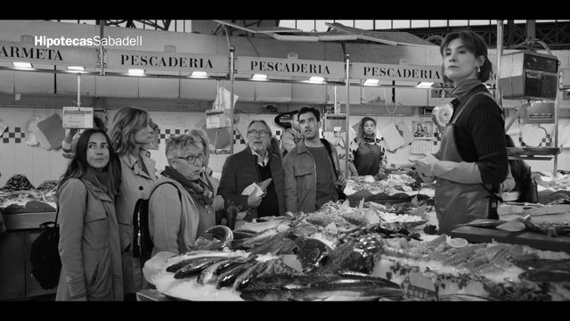 Video Reference: fish market, seafood, vendor, customers, indoor market, black and white, people, counter, fresh fish, shopping, market stall, spanish signage