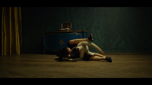 Video Reference: indoor, floor, wrestling, dance, performance, dimly lit, studio, cabinet, curtain, pose, motion, drama, martial arts