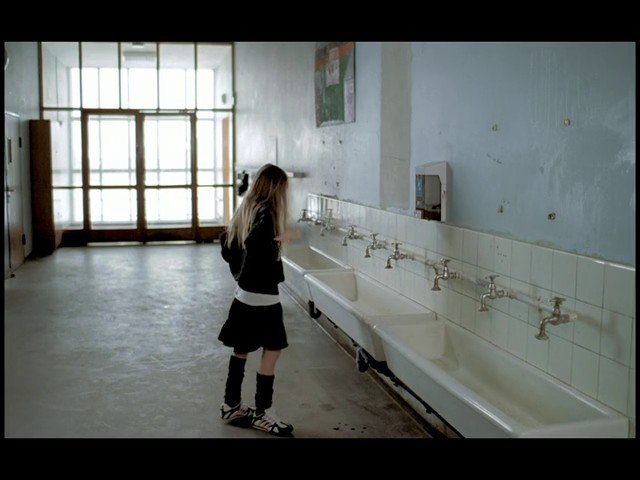 Video Reference: indoor, washroom, sinks, faucets, person, standing, windows, glass door, empty room, tile, concrete floor, hallway, school-like, utility room
