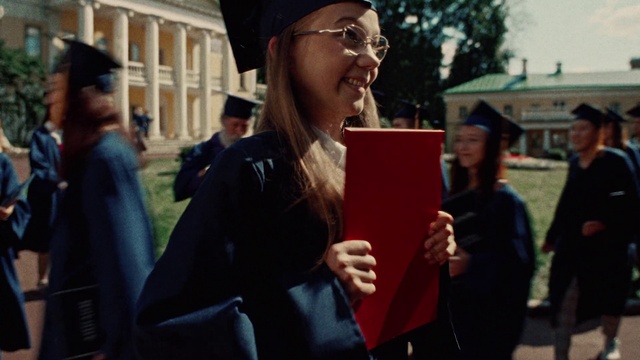 Video Reference: Hand, Outerwear, Smile, Fashion, Window, Academic dress, Building, Scholar, Mortarboard, Graduation