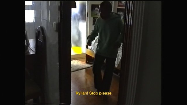 Video Reference: indoor, hallway, doorway, person, bedroom, home, dim light, backlit, subtitles, standing, interior, night