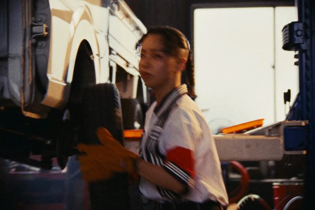 Video Reference: person, gloves, vehicle, truck, garage, workshop, industrial, equipment, maintenance, repair, mechanic, indoor, side view, machinery, workwear