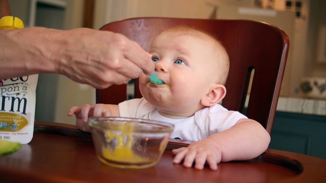 Video Reference: Cheek, Facial expression, Tableware, Mouth, Baby playing with food, Drinkware, Food, Chair, Baby & toddler clothing, Finger
