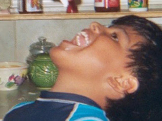 Video Reference: child, indoor, side profile, portrait, open mouth, shelves, containers, cups, casual, home, close-up, smiling, head tilt