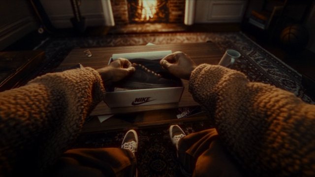 Video Reference: first-person, hands, shoebox, sneakers, living room, coffee table, indoor, unboxing, casual, home interior, warm lighting, floor rug, footwear, box