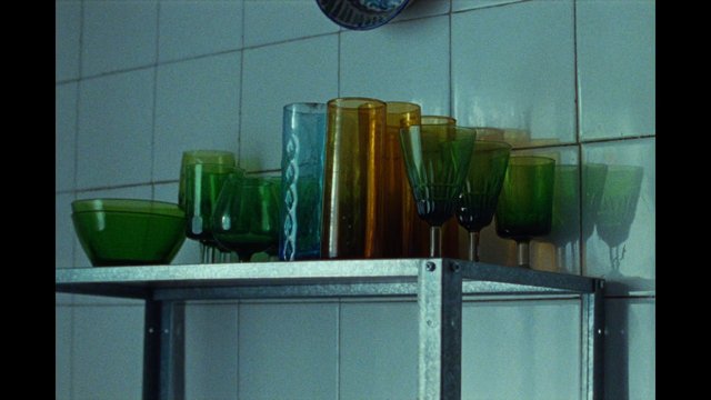 Video Reference: glassware, shelf, kitchen, tiles, bowls, drinking glasses, colored glass, green, amber, blue, interior, storage, metal shelf, home, still life