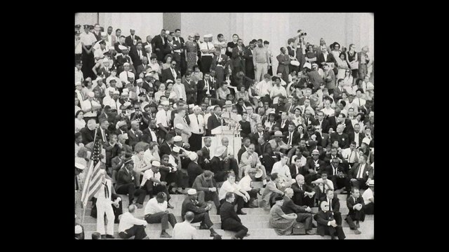 Video Reference: crowd, assembly, podium, speakers, microphones, audience, steps, indoor, black and white, historic, political, event, flag, gathering, press
