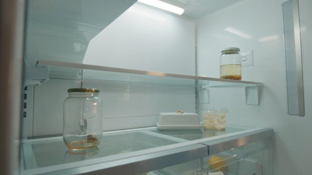 Video Reference: refrigerator, fridge interior, empty shelf, glass jar, butter dish, food storage, kitchen, household, open door, minimal, leftovers, shelf, appliance, interior