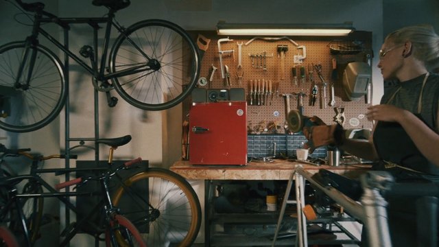 Video Reference: bicycle, bike shop, workshop, repair, tools, pegboard, garage, maintenance, workbench, hanging bike, mechanic, indoor, DIY, red fridge, person
