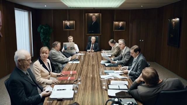 Video Reference: Table, Furniture, Conference room table, Chair, Desk, Coat, Suit, Curtain, Event, Official