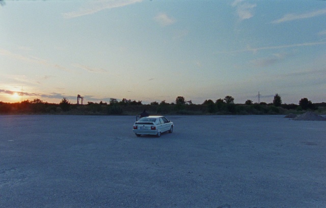 Video Reference: Sky, Cloud, Car, Vehicle, Asphalt, Tree, Landscape, Water, Horizon, Motor vehicle