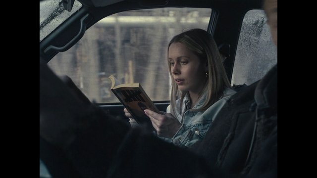 Video Reference: car interior, back seat, woman, reading, book, rainy window, city, travel, commute, portrait, denim jacket, daytime, quiet, focused, vehicle, blurred background