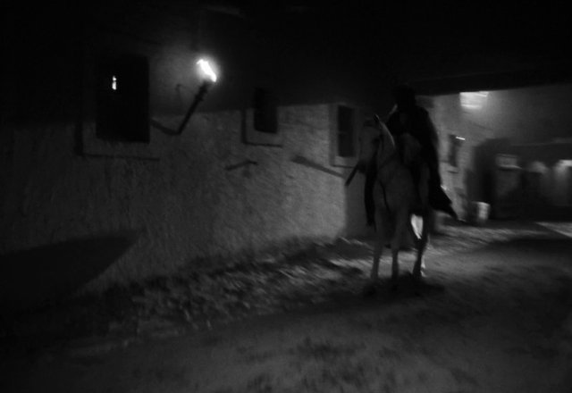 Video Reference: night, black and white, horse, rider, person, building, street, dark, blurred, outdoors, silhouette, low light, urban, motion blur