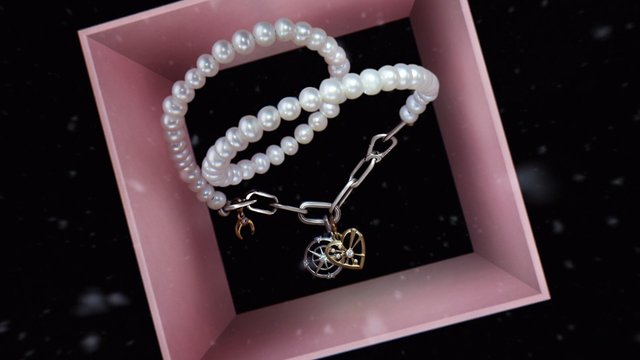 Video Reference: pearl necklace, jewelry, necklace, charms, silver chain, pink frame, product display, accessory, luxury, close-up, still life, fashion