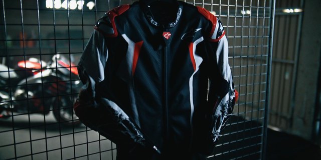 Video Reference: motorcycle, racing jacket, protective gear, helmetless, garage, fence, sportswear, biker, vehicle, dark lighting, close-up, outdoor, motorbike, urban, safety gear