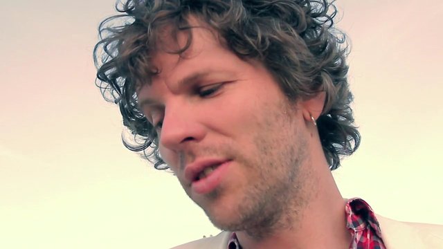 Video Reference: man, close-up, portrait, curly hair, outdoors, sky, neutral expression, face, headshot, natural light
