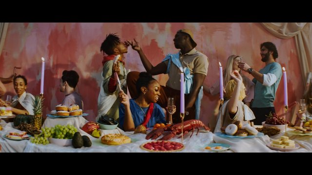 Video Reference: banquet, party, group, dining, desserts, fruit, lobster, candles, drinks, indoor, celebration, table setting, social gathering, colorful backdrop, people, festive
