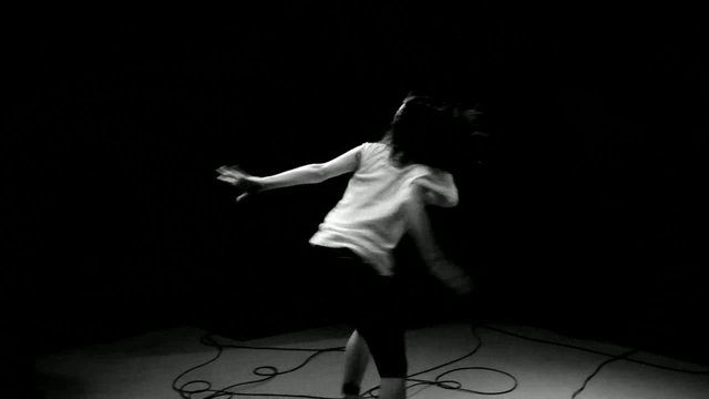 Video Reference: black and white, person, dance, motion blur, studio, dark background, performance, movement, silhouette, cables, minimalist, indoor, artistic, dynamic, figure
