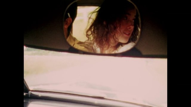 Video Reference: car, rearview mirror, reflection, woman, driving, interior, windshield, dashboard, road trip, close-up, vehicle, portrait, sunlight