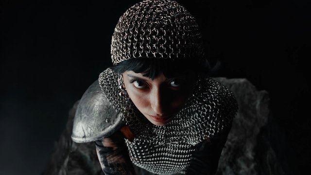 Video Reference: chainmail, armor, helmet, portrait, dark background, dramatic lighting, medieval, warrior, costume, close-up, fantasy, intense gaze