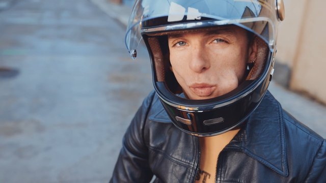 Video Reference: person, motorcycle helmet, helmet, close-up, portrait, leather jacket, outdoor, transportation, rider, face, safety gear, urban
