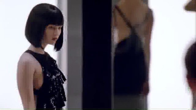 Video Reference: woman, indoor, portrait, black dress, bob haircut, mirror, fashion, standing, reflection, minimal background