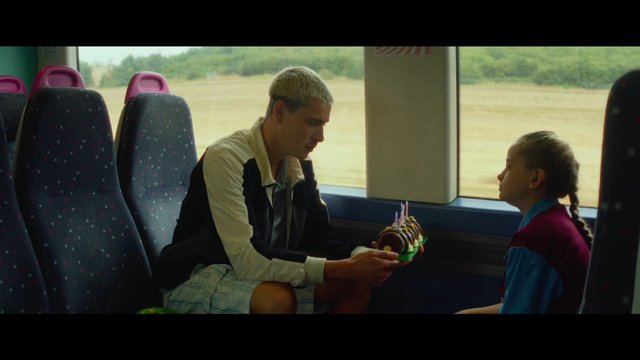 Video Reference: train, interior, man, girl, cake, dessert, gift, window, travel, conversation, seated, portrait, family, candid, celebration, bus