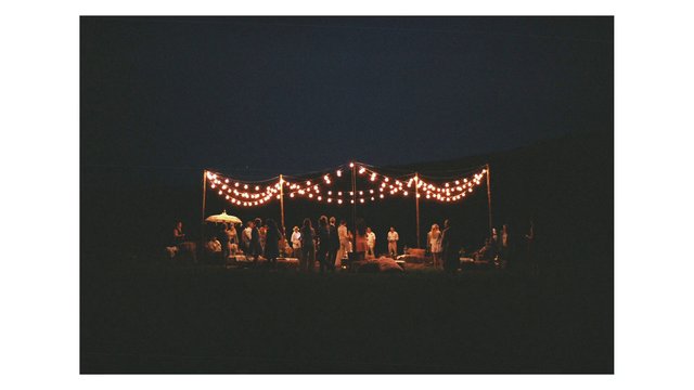 Video Reference: night, outdoor, gathering, party, string lights, people, event, dark, warm light, festival, social, crowd, camping, evening, scene