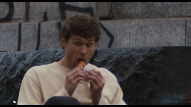 Video Reference: young man, eating, snack, outdoors, graffiti, wall, casual clothing, portrait, street scene, close-up, urban, person