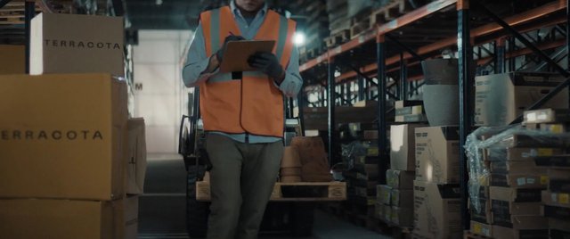 Video Reference: warehouse, worker, safety vest, clipboard, shipping boxes, inventory, logistics, storage, industrial, distribution, cargo, shelves, packaging, mammove