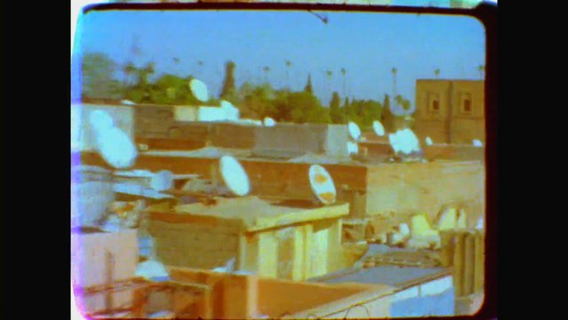 Video Reference: rooftop, satellite dishes, urban, buildings, cityscape, outdoor, brick, sky, television, blurry, low resolution, architecture