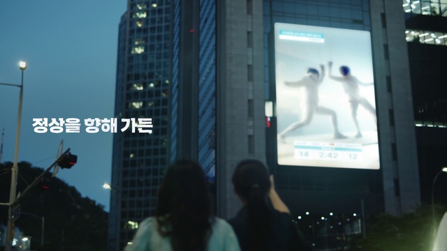 Video Reference: Building, Sky, Font, City, Metropolitan area, Display device, Facade, Signage, Event, Tower block