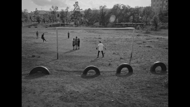 Video Reference: children, soccer, football, outdoor field, goal, playground, sports, black and white, youth, community, rural, practice, tires, landscape, active, game