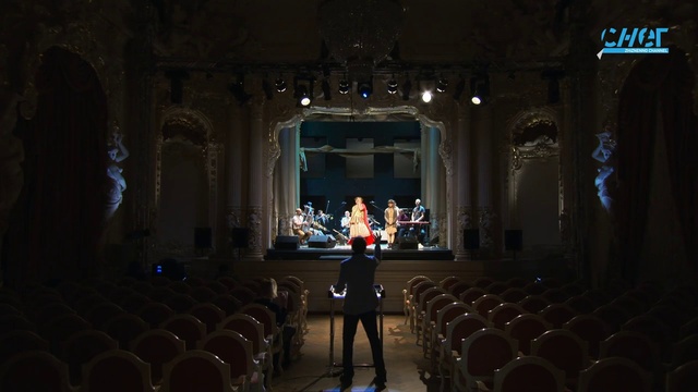 Video Reference: Musical instrument accessory, Chair, Entertainment, Hall, Building, Performing arts center, Performing arts, Event, Projection screen, Darkness