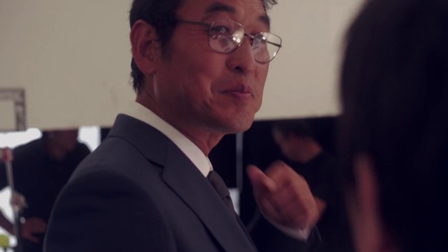 Video Reference: Forehead, Glasses, Vision care, Gesture, Microphone, Dress shirt, Suit, Eyewear, Blazer, Formal wear