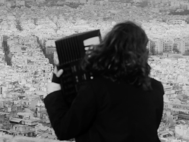 Video Reference: Human, Photographer, Standing, Black-and-white, Camera, Flash photography, Style, Camera lens, Wall, Digital camera