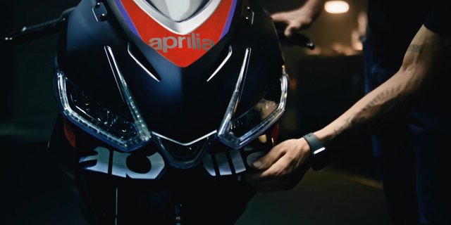Video Reference: motorcycle, sportbike, front view, close-up, mechanic, garage, headlights, fairing, hands, indoor, dark lighting, vehicle, repair, racing, transportation
