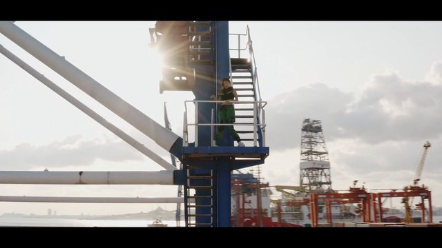 Video Reference: port, shipyard, industrial, crane, stairs, backlit, sunlight, harbor, metal structure, person, outdoor, waterfront