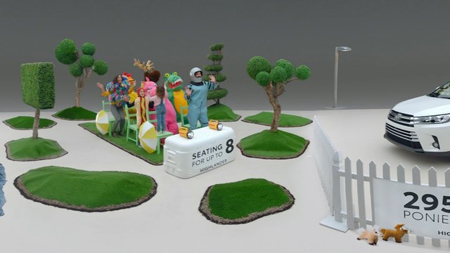 Video Reference: costume, people, car, staged, colorful, artificial trees, grass patches, fence, indoor, commercial, playful, group, props, vehicle, display, studio