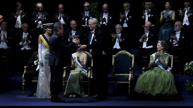 Video Reference: Hat, Entertainment, Chair, Performing arts, Suit, Event, Formal wear, Music, Uniform, Crowd