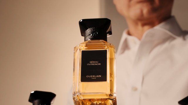 Video Reference: perfume, fragrance, bottle, luxury, product shot, close-up, cosmetics, elegant, amber liquid, glass bottle, black cap, commercial, beauty, men's shirt, blurred background