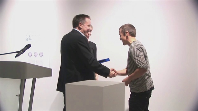 Video Reference: Smile, Shoulder, Podium, Gesture, Lectern, Font, Audio equipment, White-collar worker, Microphone, Event