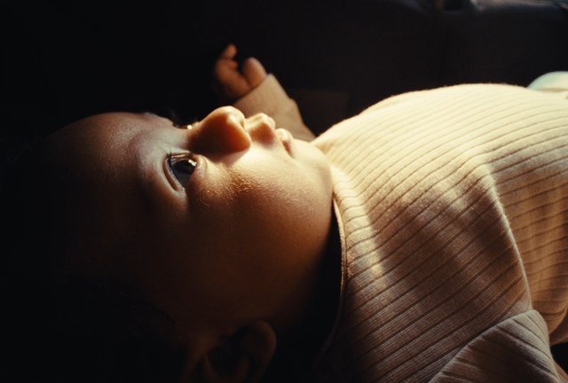 Video Reference: baby, infant, close-up, portrait, sleeping, lying down, sunlight, warm light, soft focus, outfit, nursery, peaceful, child, flesh tones