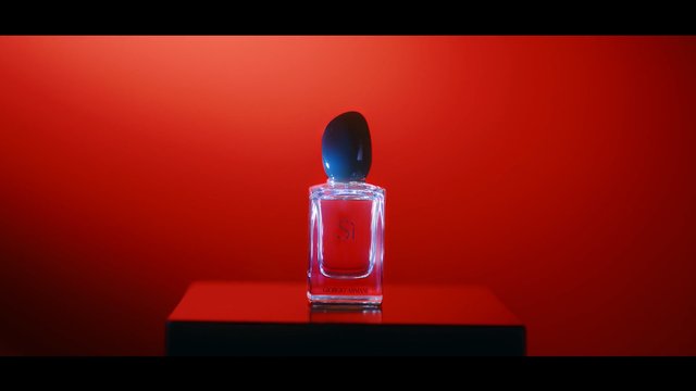 Video Reference: perfume, fragrance bottle, cosmetic product, glass bottle, black cap, red background, studio lighting, product shot, luxury, minimalist, still life