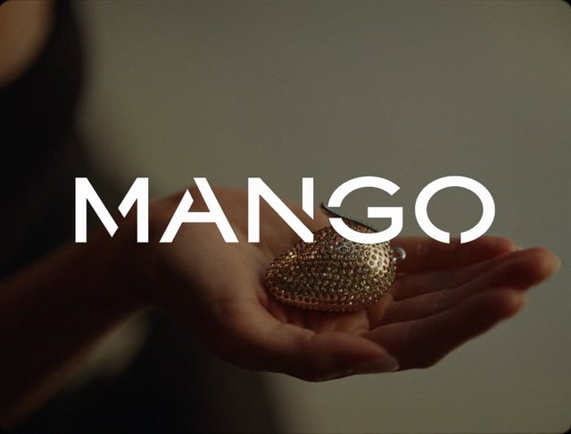 Video Reference: hand, metal object, close-up, product shot, text overlay, mango, jewelry, ornament, studio lighting, macro, palm, abstract, advertisement