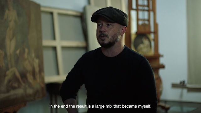 Video Reference: Flat cap, Hairstyle, Cap, Beard, Sleeve, Flash photography, Standing, Facial hair, Street fashion, Window